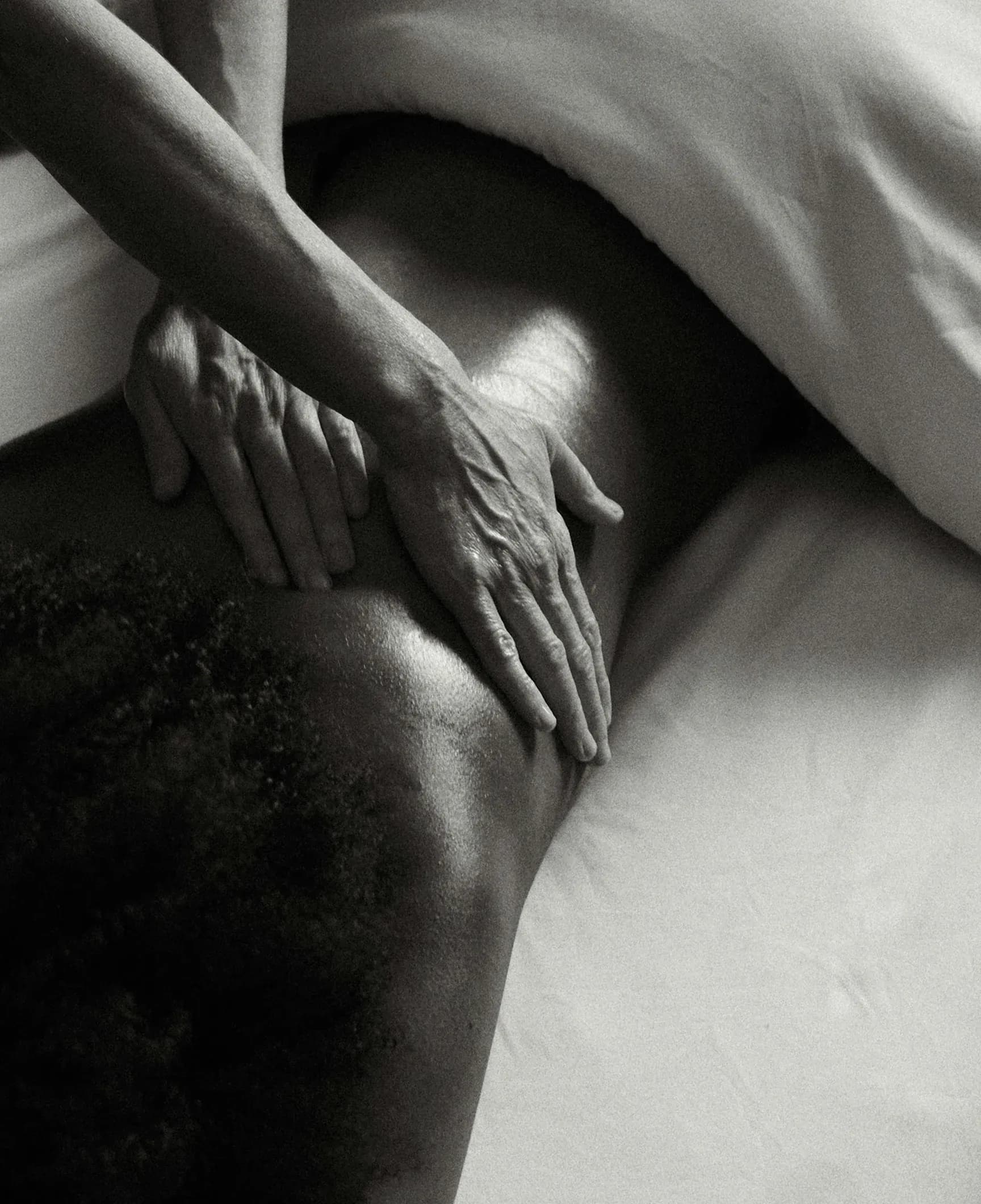 Rückenmassage: Hände einer Therapeutin auf dem Rücken einer liegenden Person, Schwarz-Weiß-Aufnahme