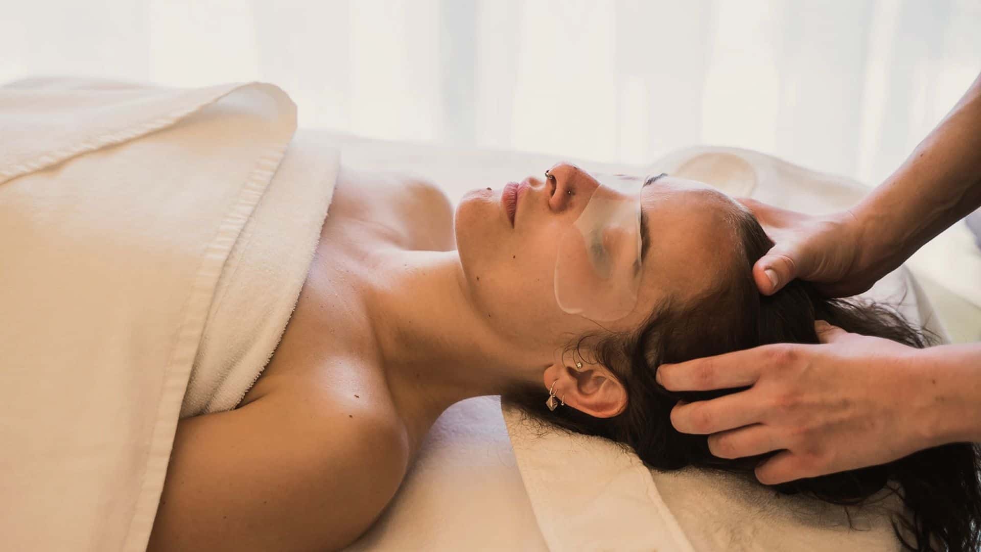 Kosmetikerin gibt einer Frau bei einer Gesichtsbehandlung eine sanfte Kopf- und Gesichtsmassage.